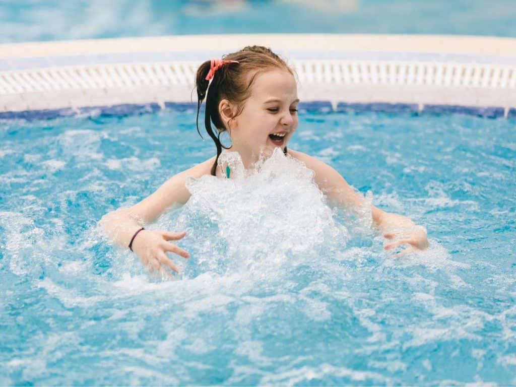 Petite fille qui s'amuse avec les jets d'eau dans un spa