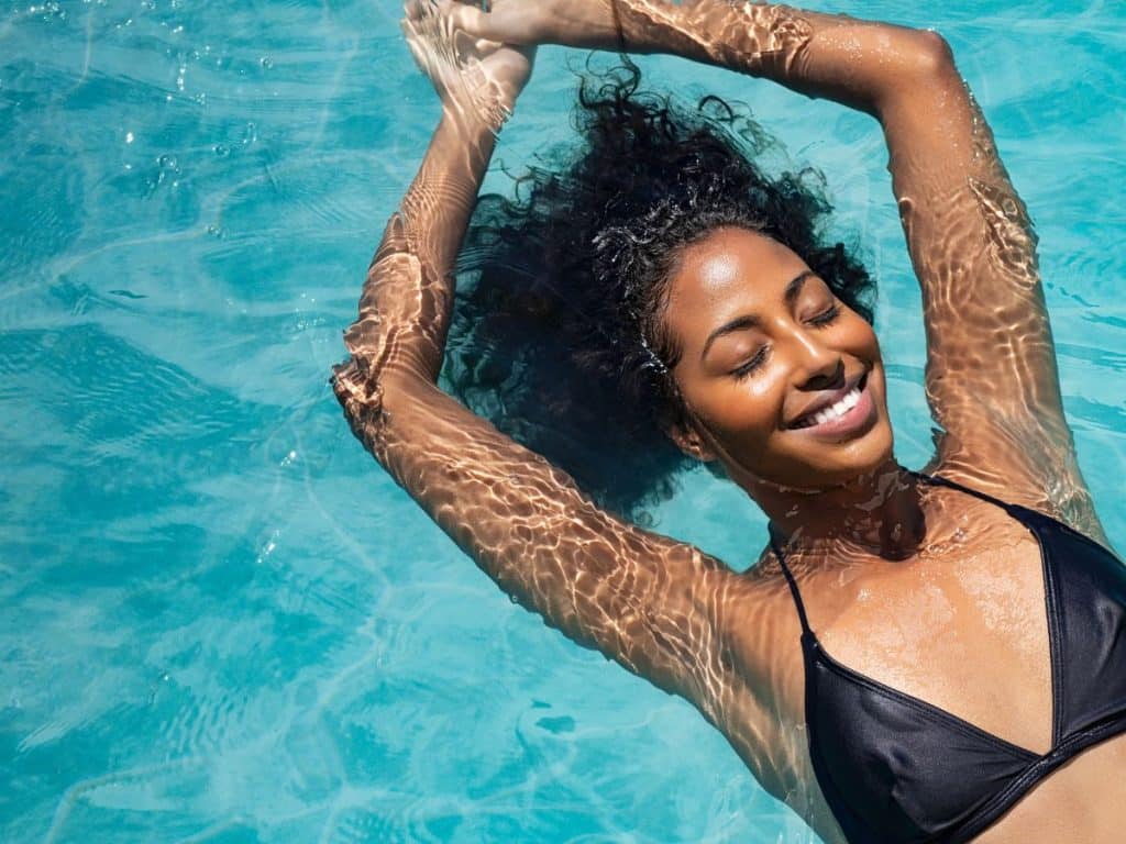 Jeune femme qui se détend dans sa piscine en été