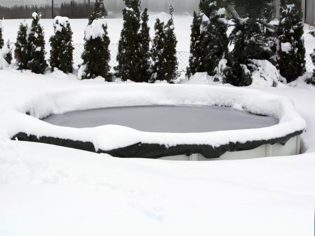 Piscine hors sol sous la neige avec une couverture étanche d'hiver