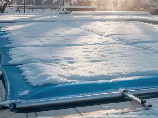 Bâche d'hivernage recouverte de neige protégeant une piscine durant l'hiver
